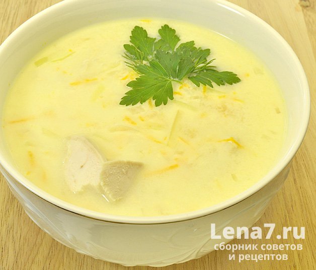 Готовый суп с плавленым сыром в порционной тарелке, украшенный зеленью