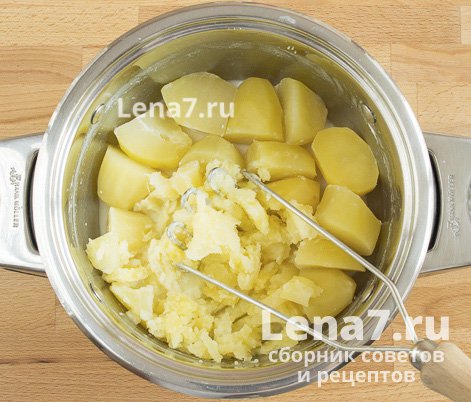 Картофель в кастрюле, разминаемый картофелемялкой