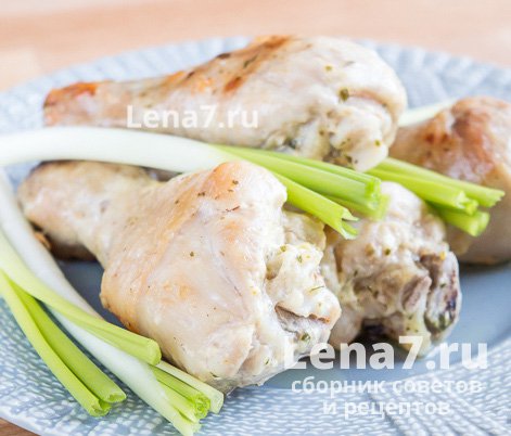 Готовые жареные куриные ножки на тарелке с зеленым луком